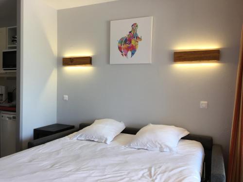 a bedroom with a white bed with two pillows at Studio sur le Domaine du Golf de Pont Royal in Mallemort