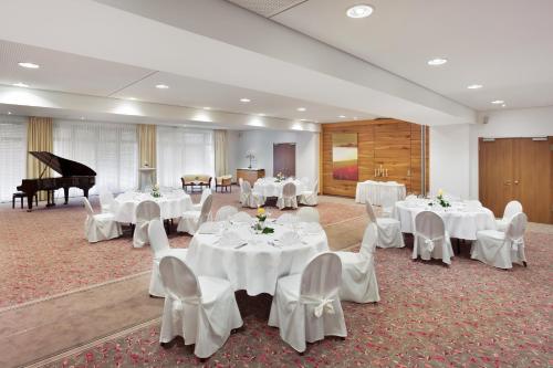 a room with white tables and chairs and a piano at Holiday Inn Nürnberg City Centre by IHG in Nürnberg