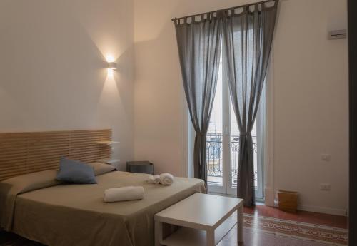 a bedroom with a bed with a table and a window at Piazza Florio Rooms in Palermo