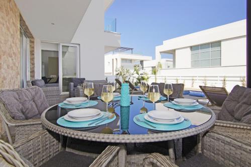 a table with plates and wine glasses on a patio at Villa Medusa in Protaras