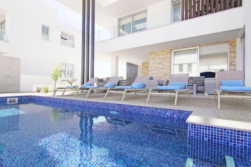 a swimming pool with chairs and a building at Villa Medusa in Protaras