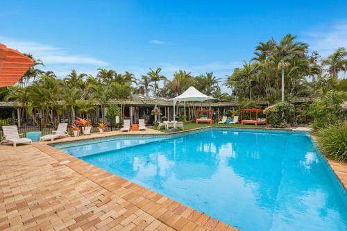 a swimming pool in a resort with palm trees at Ballina Beach Resort in Ballina