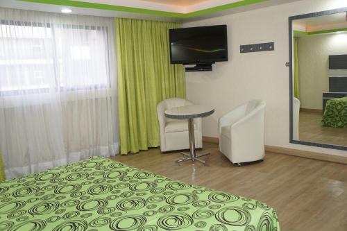 a room with a bed and a table and a television at Hotel Corona Real in Mexico City