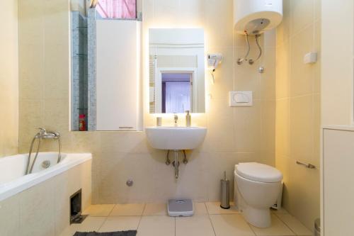 W łazience znajduje się umywalka, toaleta i lustro. w obiekcie Jevrejska - Central Apartment with Free Parking w Nowym Sadzie