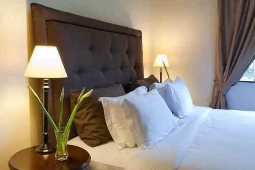 a bedroom with a bed with white pillows and two lamps at Palacina The Residence & The Suites in Nairobi