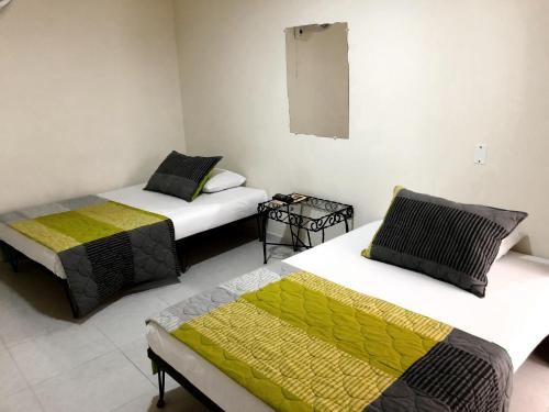 a room with two beds and a mirror on the wall at Hotel Morfeo in Tuluá