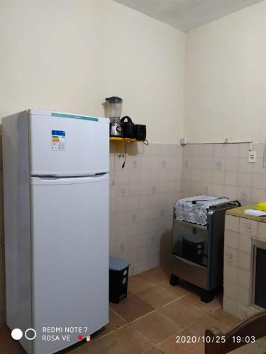 a kitchen with a white refrigerator and a stove at Temporada no Paraíso in Ilha Comprida