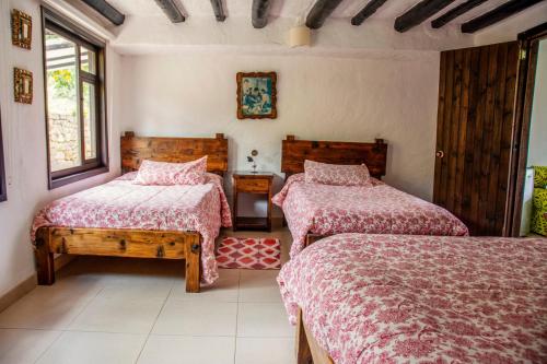 a bedroom with two beds and two windows at Villa Patty in Tibasosa