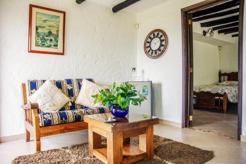 a living room with a couch and a table and a clock at Villa Patty in Tibasosa