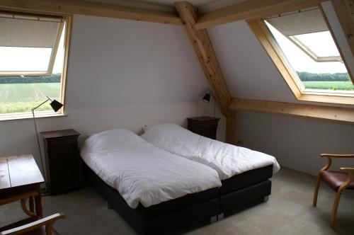 a bed in a room with two windows at B&B de Luijenbergh in Oud-Gastel