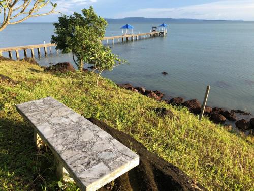 a stone bench sitting on a hill next to a pier at Koh Mak Buri Hut Natural Resort in Ko Mak