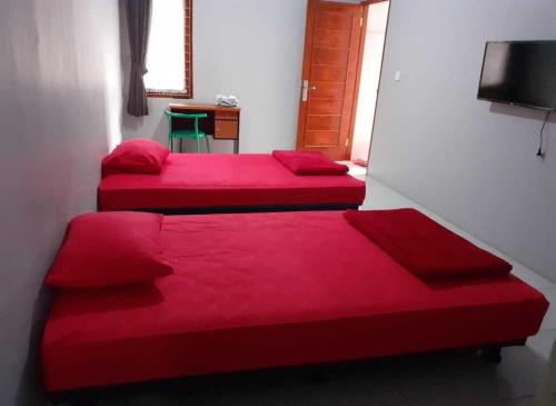 two beds in a room with red sheets at Nabila Syar'i Guest House in Padalarang
