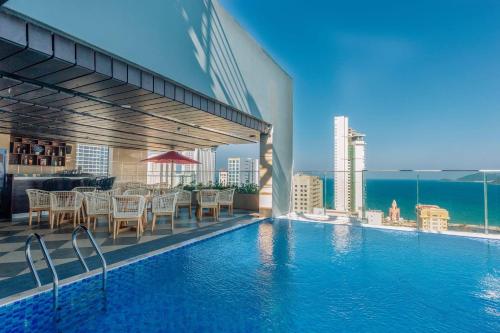 a swimming pool with tables and chairs on a building at LeMore Hotel Nha Trang in Nha Trang