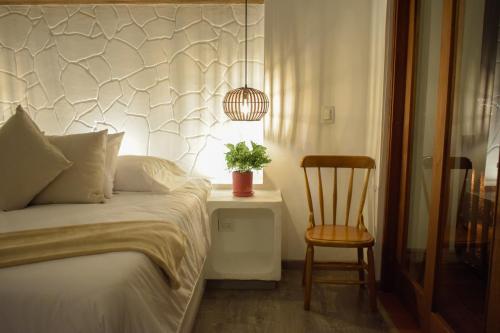 a bedroom with a bed and a chair and a potted plant at Hotel El Embrujo in Villa de Leyva