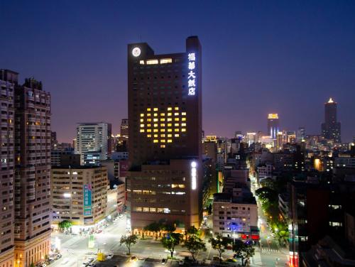 a tall building with a clock on it in a city at The Howard Plaza Hotel Kaohsiung in Kaohsiung