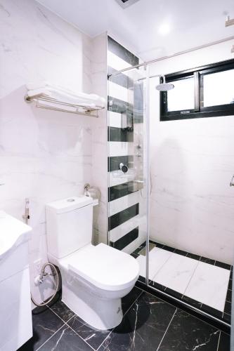 a white bathroom with a toilet and a shower at 似禾苑民宿 Siheyuan Homestay in Sanxing