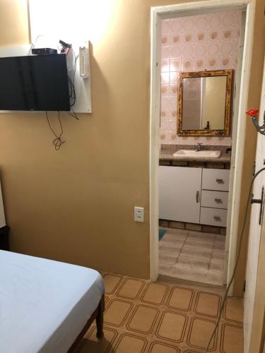 Un dormitorio con una cama, un lavabo y un espejo. en O Mar Hospedagem - SUÍTES PRIVADAS, en Arraial do Cabo