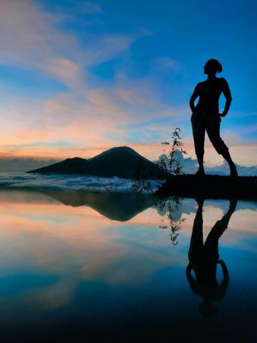 a person running with their reflection in the water at Batur Volcano Guesthouse in Kintamani