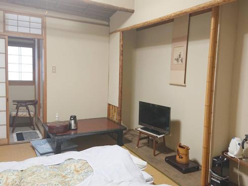 a room with a bed and a table and a tv at Cooking inn Kagetsu - Vacation STAY 88535 in Kuradani