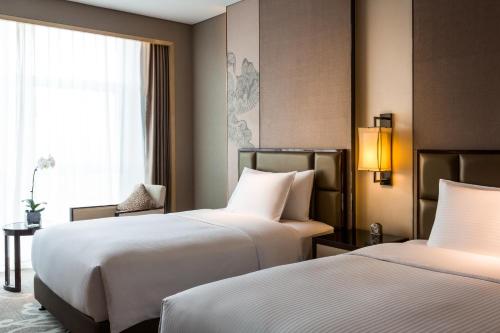 a hotel room with two beds and a window at Pullman Weifang in Weifang