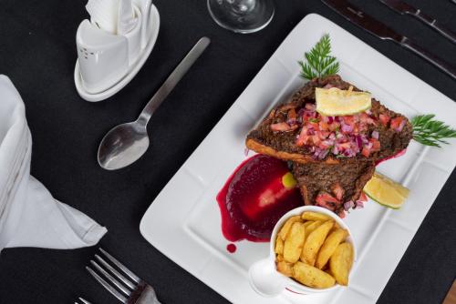 a white plate of food with a sandwich and fruit at Lake Elementaita Mountain Lodge in Nakuru
