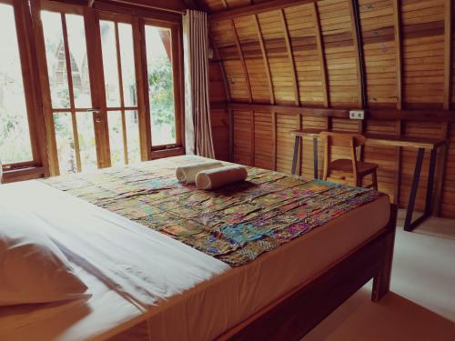 ein großes Bett in einem Zimmer mit Fenstern in der Unterkunft Coconut Tree Cottages in Batukaras