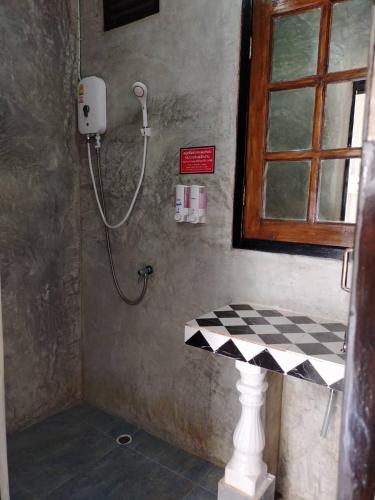 a shower in a bathroom with a checkered floor at At Night in Chumphon