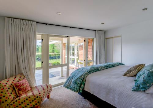 a bedroom with a bed and a chair and a window at Gem bed and breakfast in Christchurch