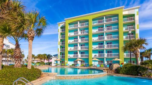 a hotel with a swimming pool and palm trees at Holiday Inn Express Orange Beach - On The Beach by IHG in Orange Beach