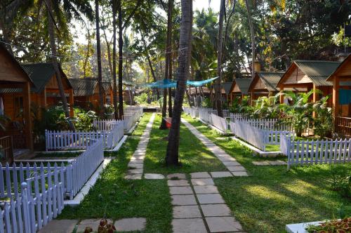 een rij cottages met witte hekken en bomen bij Kings Villa Resort in Palolem