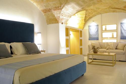 a bedroom with a large bed and a couch at La Dimora delle Fate Luxury & SPA in Miggiano