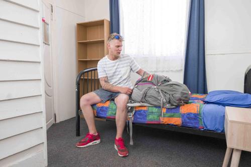 a man sitting on a bed with a backpack at Dolphin Retreat Bunbury in Bunbury
