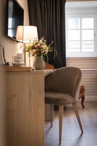 a desk with a vase of flowers and a lamp at Hôtel Le Rohan, centre Cathédrale in Strasbourg