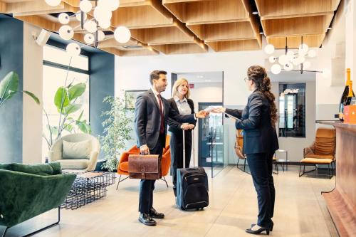a man and woman shaking hands in a lobby at Novotel Parma Centro in Parma
