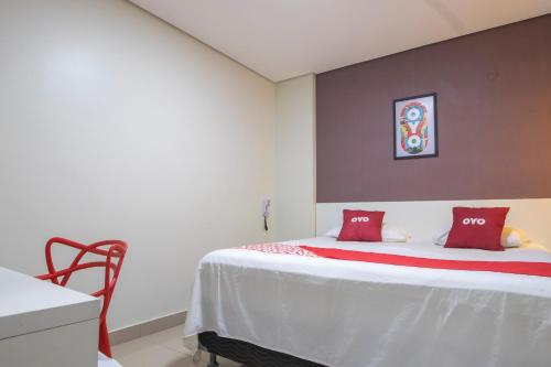 a bedroom with a bed with red pillows on it at OYO Tropical Confort Hotel, Brasilia in Brasilia
