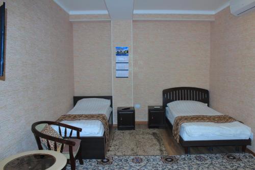two beds in a room with two chairs and a table at Хотел Хесон in Khujand
