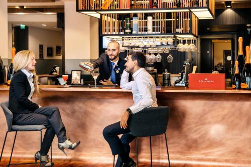 a man and a woman sitting at a bar at Novotel Parma Centro in Parma