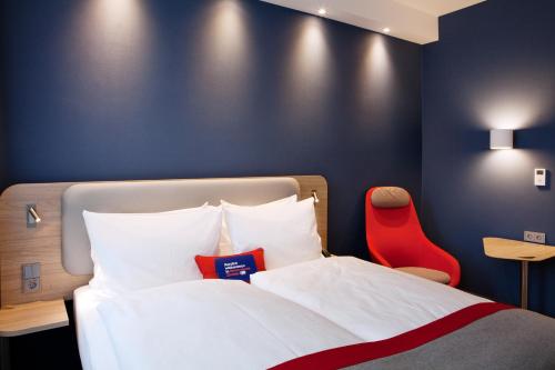 a bedroom with a bed and a red chair at Holiday Inn Express - Kaiserslautern by IHG in Kaiserslautern