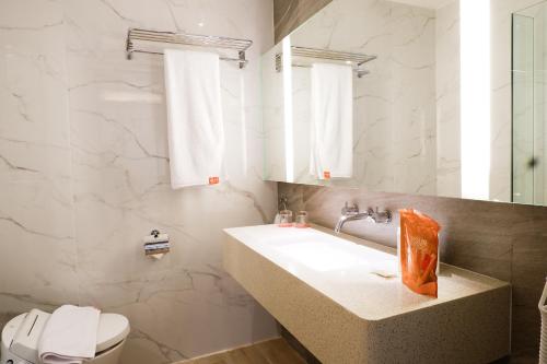 uma casa de banho branca com um lavatório e um WC em HARRIS Hotel and Conventions Kelapa Gading Jakarta em Jakarta