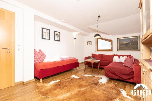a living room with a red couch and a table at HORBERG Appartements in Schwendau