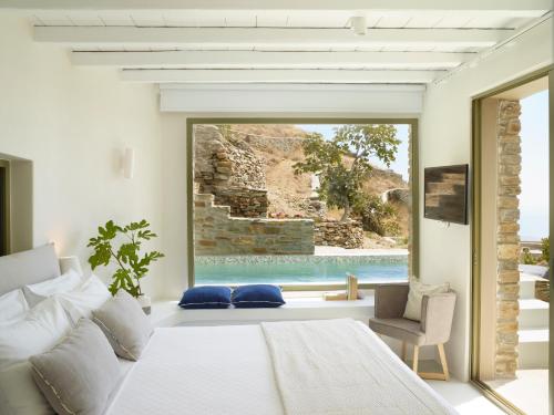 a bedroom with a bed and a view of a pool at Aeolis Tinos Suites in Tinos Town