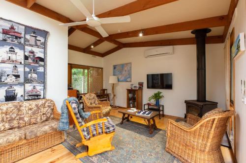 a living room with a couch and chairs and a wood stove at Merricks Surf Cottage - Charming Beachfront Bliss in Merricks
