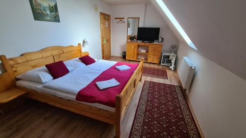 a bedroom with a wooden bed with a red blanket at Hotel Koliba in Senec