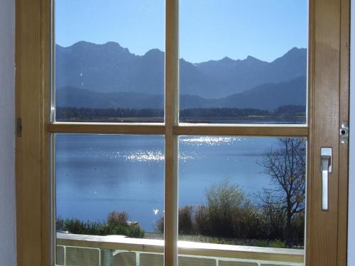 a window looking out at a view of a lake at Gästehaus Guggomos "Hopfen am See" in Füssen