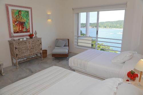 a bedroom with two beds and a window with a view at 1031 - Villas Carey Condo in Santa Maria Huatulco