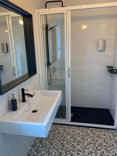La salle de bains est pourvue d'un lavabo blanc et d'une douche. dans l'établissement Casa da Oliveira, à Poio