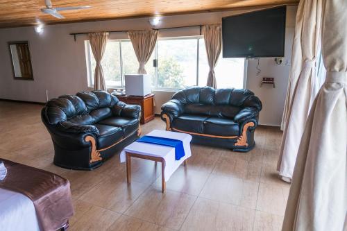 a living room with two leather couches and a tv at Lake Safari Lodge in Siavonga