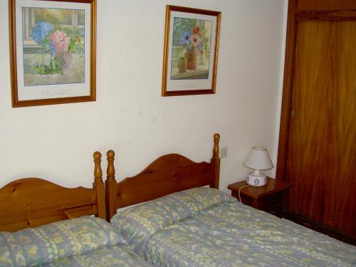 ラ・マンガ・デル・マール・メノールにあるAPCOSTAS - Hawaii Sunのベッドルーム1室(ベッド1台付)が備わります。壁に2枚の写真が飾られています。