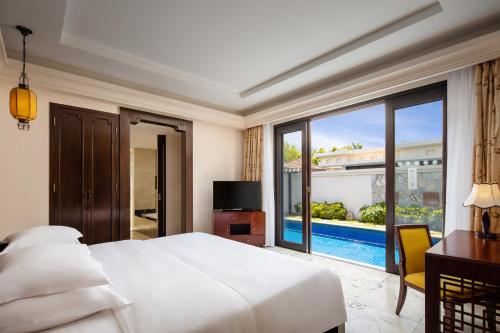 a bedroom with a bed and a view of a pool at Pullman Sanya Yalong Bay Villas & Resort in Sanya