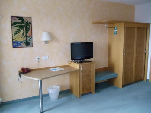 a room with a desk with a tv and a table at Weinhotel Kienle in Burrweiler